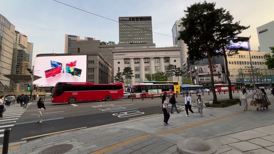 낮 도심의 대형 스크린과 버스·보행자